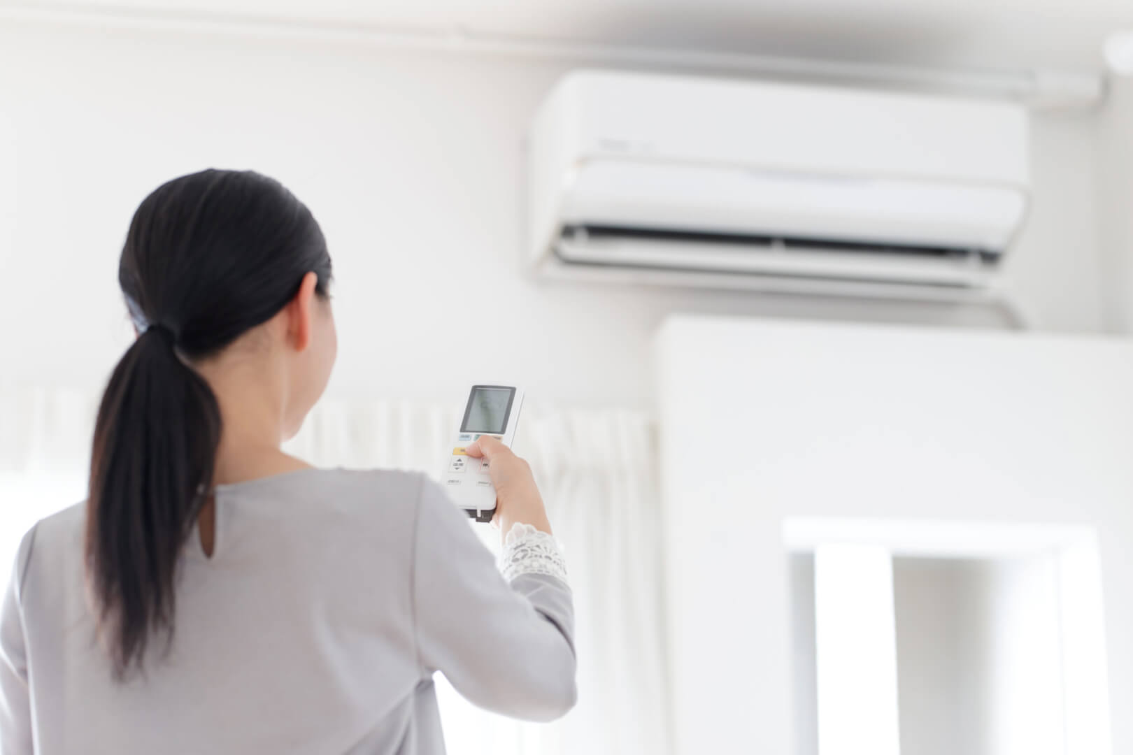 Femme réglant un climatiseur avec télécommande
